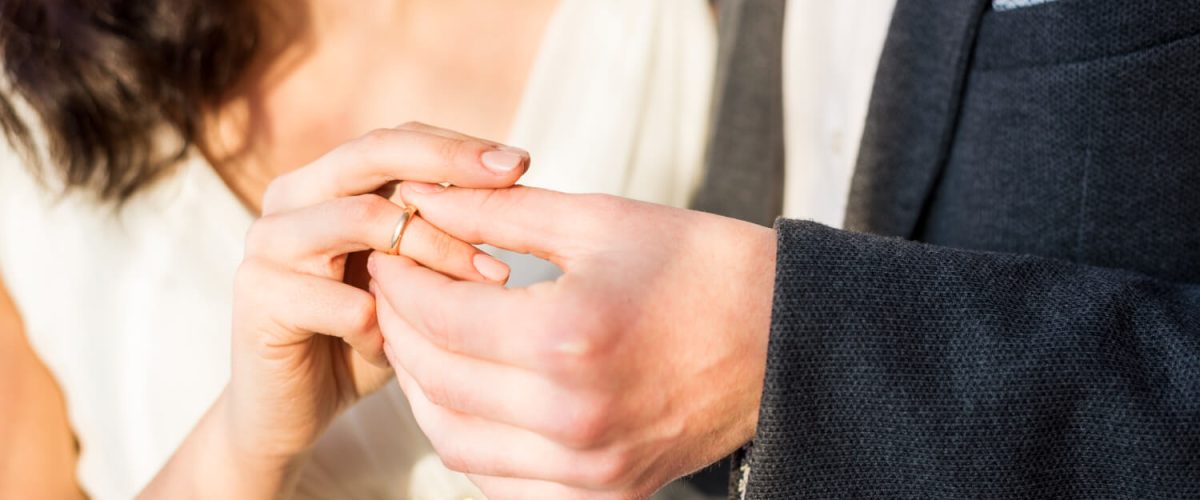Couple exchanging ring in engagement or wedding 1200x500
