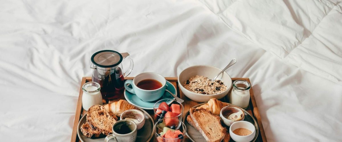 A tray of food sitting on top of a bed natalie sum DZQBffniTO8 unsplash 1200x500