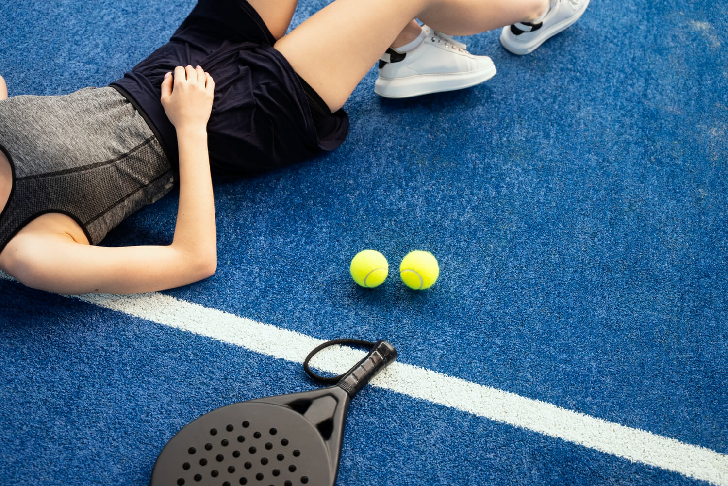 High angle tired woman laying on ground after padel